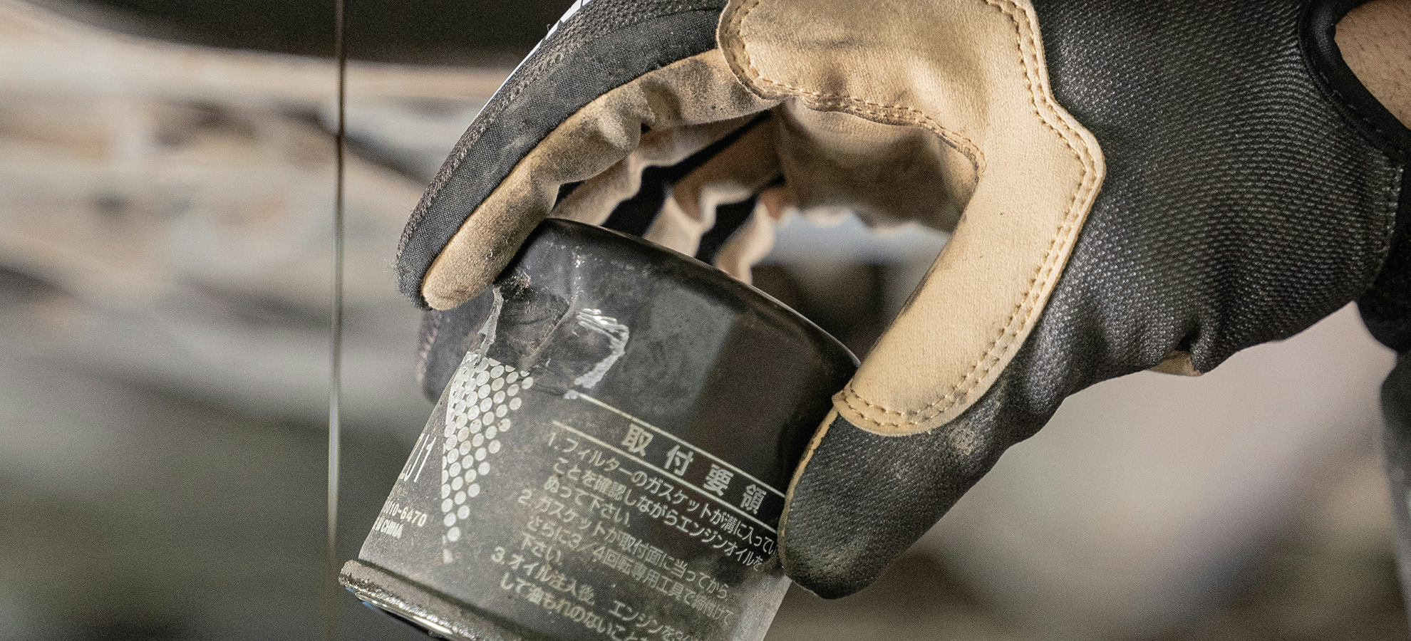 A closeup of a hand holding a motor vehicle part for the vehicle they're repairing themself