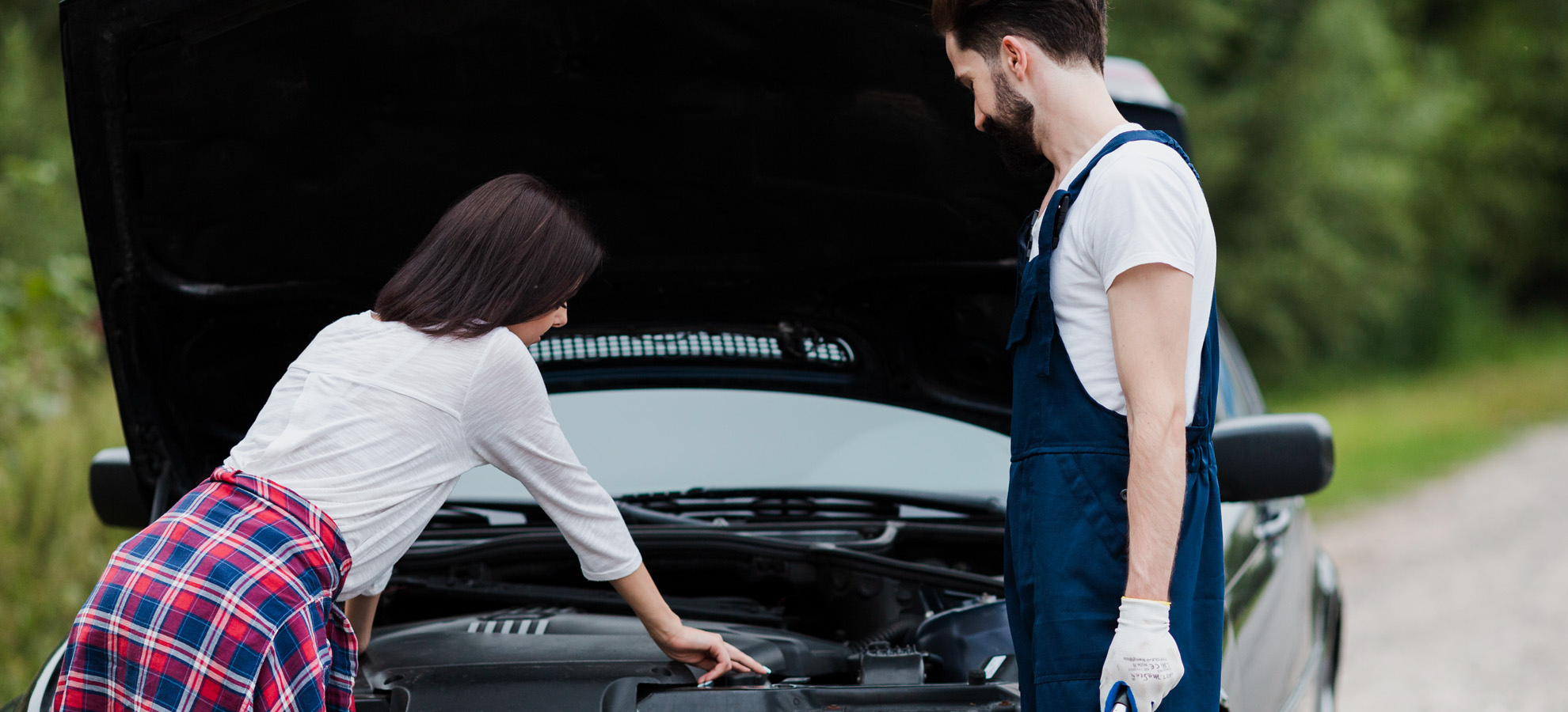A mechanic helps a woman on the side of the road after her vehicle has broken down