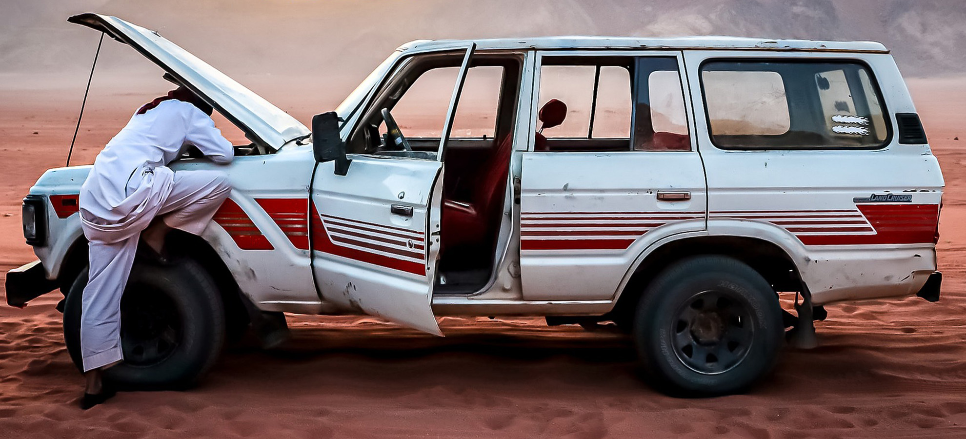 Someone broken down in an SUV in the desert due to engine issues